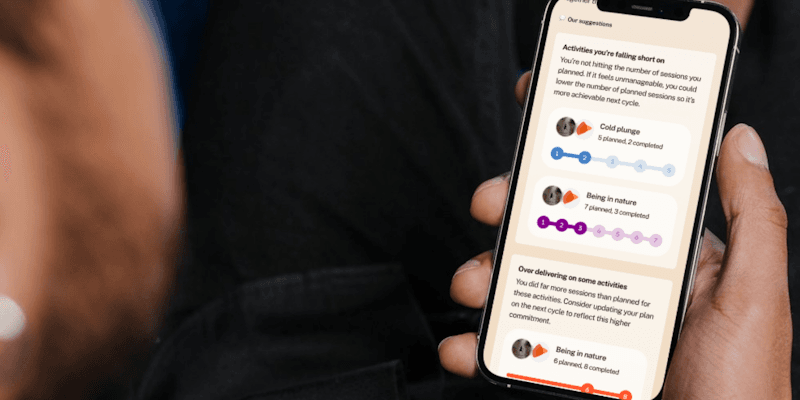 A person holding a phone showing the Bearmore app’s suggestions screen, listing activities they are falling short on and over-delivering on