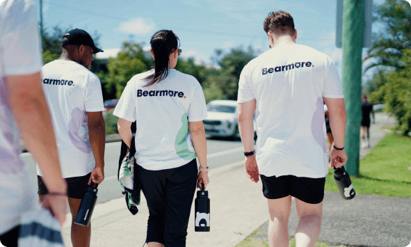 Four people in Bearmore t-shirts walking along a footpath together, seen from behind